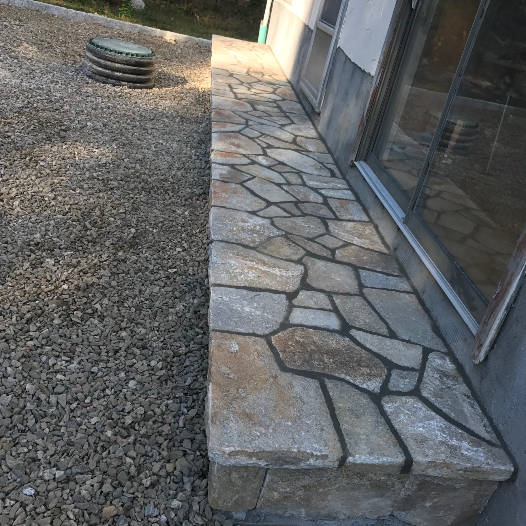 Irregular flagstone walkway along a house foundation